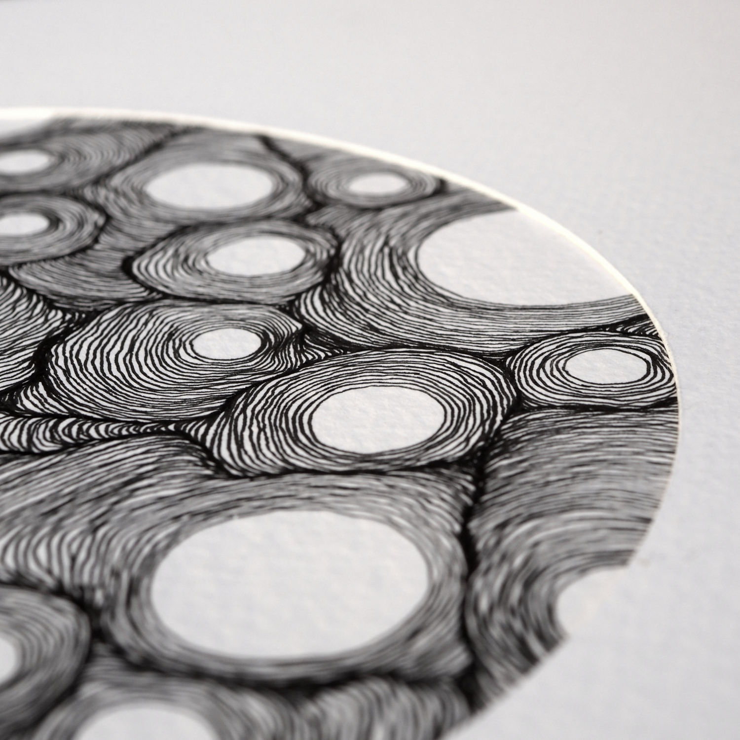 Detailed close-up of a hand-drawn line drawing created with Japanese ink, showing concentric lines emanating from 13 empty circles of varying sizes, eventually colliding onto each other, creating shadowy areas.
