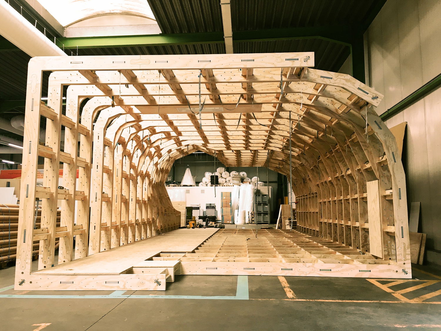 Day seven, and panels are covering about one third of the floor. Belts are hanging from the ceiling and the skylight projects a dramatic light through the open woodwork.