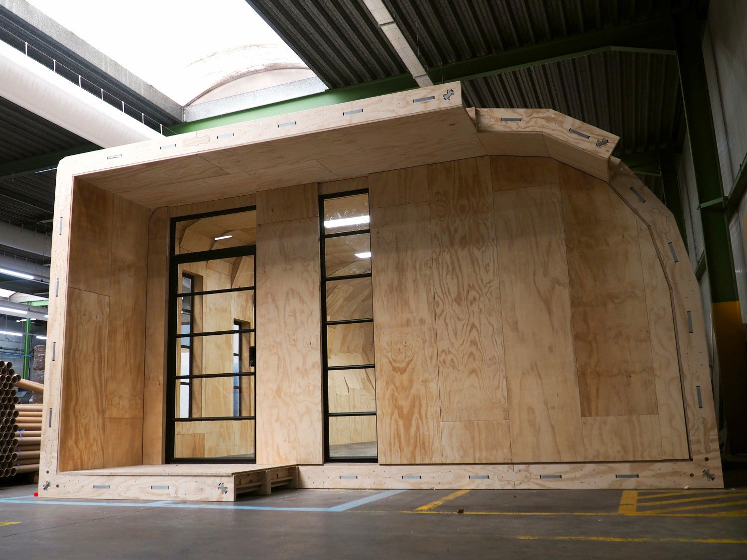 A view outside the plywood QuadriVille space looking at the right entrance with a black metal and glass door.