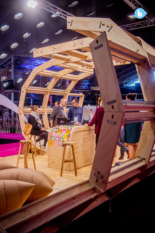 A close-up view of the modular structure of the exhibition stand, highlighting the puzzle-like assembly of plywood parts held together by tension belts.